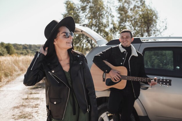 Foto feliz pareja viajera vestida con ropa elegante negra disfrutando de un viaje en coche