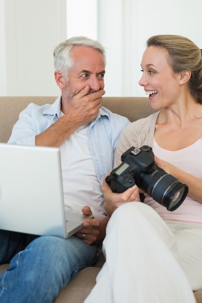 Feliz pareja viendo sus fotos en la computadora portátil
