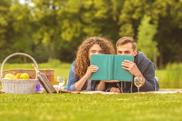 La feliz pareja yacía con un libro en el picnic.