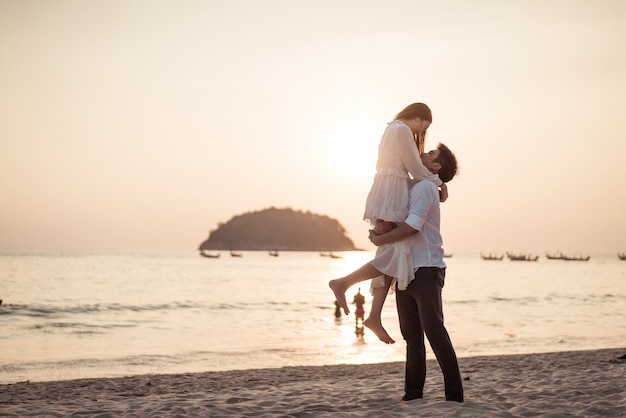 Feliz pareja yendo de viaje de luna de miel en la playa de arena tropical en verano