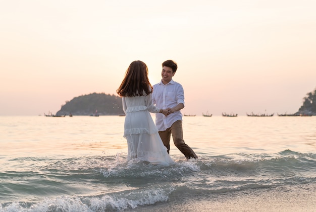 Feliz pareja yendo de viaje de luna de miel en la playa de arena tropical en verano