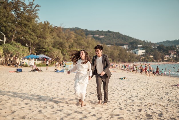 Feliz pareja yendo de viaje de luna de miel en la playa de arena tropical en verano