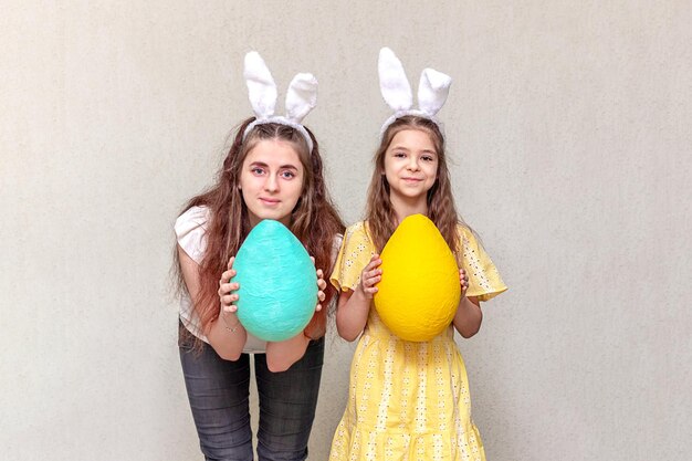Feliz Páscoa Duas meninas vestindo orelhas de coelho de Páscoa seguram ovos de Páscua em suas mãos Copiar espaço