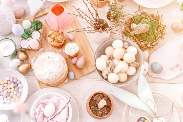 Feliz páscoa e férias de primavera tempo festivo tablescape decoração tradicional jantar comida ovos de páscoa e bolos assados na mesa em casa pop pálido azul pastel e cor rosa vista superior flare