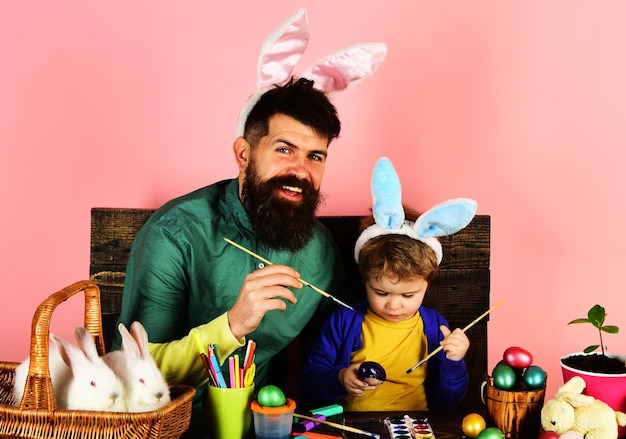 Foto feliz páscoa família em orelhas de coelho pintando ovos pai e filho se preparando para férias