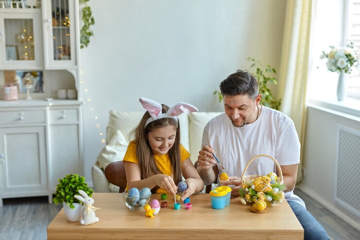 Feliz Páscoa. Família pintou ovos em casa. Pai e filha usando orelhas de coelho