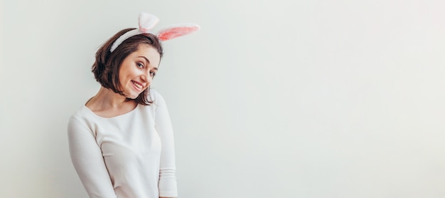 Foto feliz páscoa feriado celebração primavera conceito. orelhas vestindo do coelho da jovem mulher isoladas no branco. preparação para férias. menina olhando feliz e animado se divertindo no dia de páscoa. bandeira