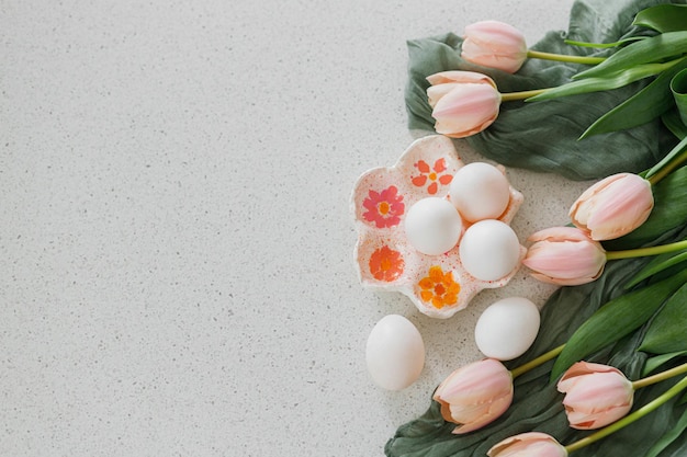 Feliz Páscoa Lindas tulipas e ovos naturais na mesa moderna Elegante páscoa plana com espaço para cópia Porta-ovos feito à mão com tulipas cor de rosa