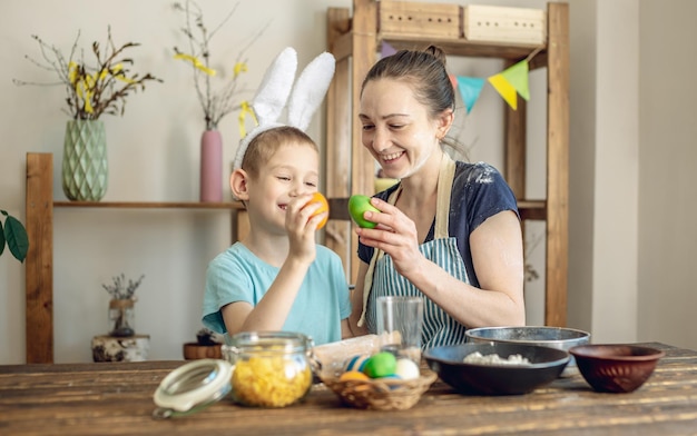 Foto feliz páscoa mãe e filho estão se preparando para a páscoa da primavera colorindo alegremente ovos de férias.