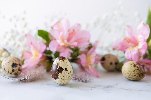 Foto feliz páscoa ovos de codorna penas primavera flores cor de rosa no fundo de mármorexa