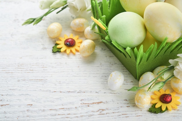 Feliz Páscoa Ovos de Páscoa e coelho na cesta verde na velha mesa de madeira branca com rosas brancas e amarelas Cartão de férias de Páscoa feliz Primavera Fundo de Páscoa com espaço para cópia Vista superior