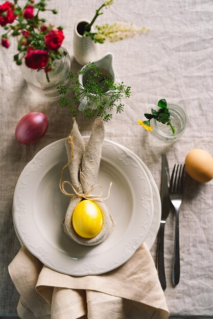 Feliz Páscoa Ovos de Páscoa elegantes em um guardanapo com flores de primavera em fundo branco de madeira Cenário de mesa O conceito de um feliz feriado de Páscoa