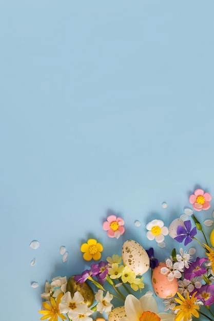 Feliz Páscoa Ovos de Páscoa flores coloridas e pétalas de cereja florescendo planas sobre fundo azul Modelo festivo elegante com espaço para texto Cartão ou banner