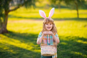 Feliz páscoa para crianças menino fantasiado de coelho com orelhas de coelho caçando ovos de páscoa no parque