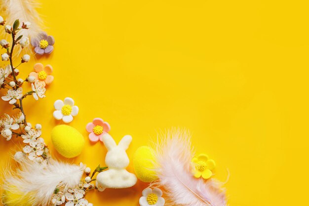 Feliz Páscoa Páscoa plana com ovos flores penas de coelho e cereja florescendo em fundo amarelo Modelo festivo moderno com espaço para texto Cartão ou banner