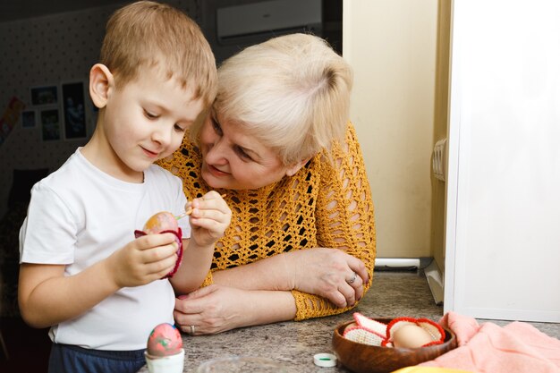 Feliz Páscoa. Uma avó e seu neto pintando ovos de Páscoa. Família feliz se preparando para a Páscoa em casa