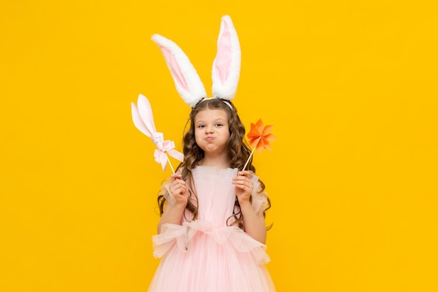 Feliz Páscoa Uma garotinha está chocada com o feriado de primavera A linda criança inflou suas bochechas Uma adolescente com orelhas de coelho em um fundo amarelo isolado