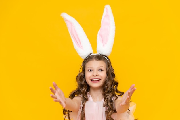 Feliz Páscoa Uma garotinha vestida de coelho celebra um feriado de primavera Uma encantadora criança sorridente em um lindo vestido com orelhas compridas em um fundo amarelo isolado