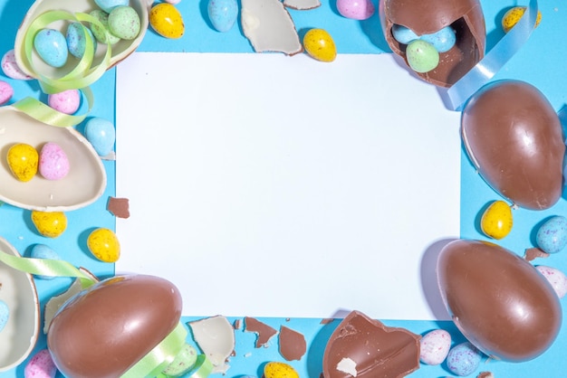 Feliz Pascua colorido flatlay Huevos de Pascua de colores brillantes y chocolate con cinta festiva de vacaciones sobre fondo azul Plantilla de promoción y compras para Pascua