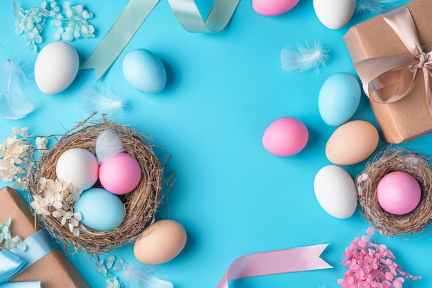 Feliz Pascua delicado fondo pastel con cajas de regalo de huevos de colores y nidos sobre un fondo azul Vista superior espacio de copia