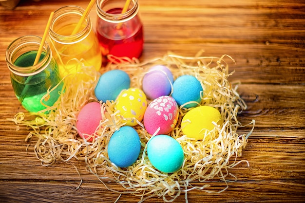 Feliz Pascua con huevos coloridos en paja. Decoración de mesa para vacaciones. Vista superior.