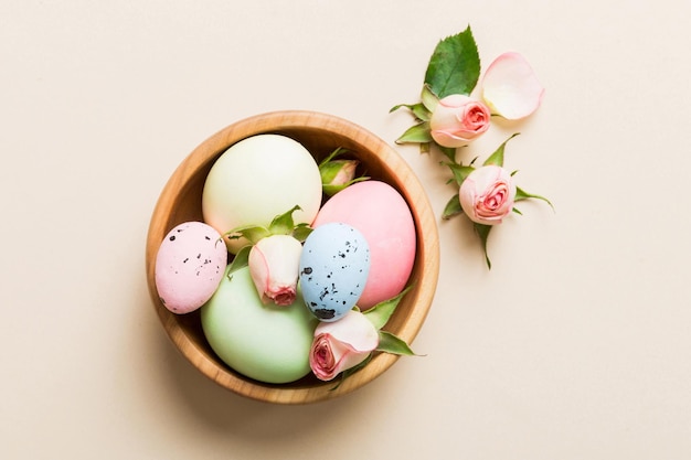 Feliz Pascua Huevos de Pascua en la canasta en la mesa de colores con rosas amarillas Huevos de colores teñidos naturales Fondo vista superior con espacio de copia