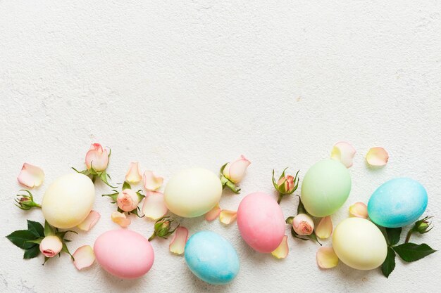 Feliz Pascua Huevos de Pascua en mesa de colores con rosas amarillas Huevos de colores teñidos naturales Fondo vista superior con espacio de copia