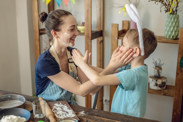 Foto feliz pascua mamá e hijo se están preparando para la pascua de primavera coloreando alegremente huevos navideños.