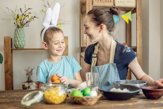 Foto feliz pascua mamá e hijo se están preparando para la pascua de primavera coloreando alegremente huevos navideños.