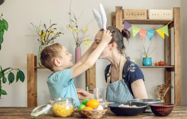 Foto feliz pascua mamá e hijo se están preparando para la pascua de primavera coloreando alegremente huevos navideños.