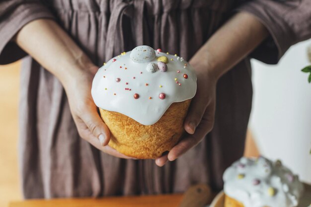 Feliz Pascua Mujer sosteniendo elegante pastel de Pascua horneado con glaseado de azúcar y chispas