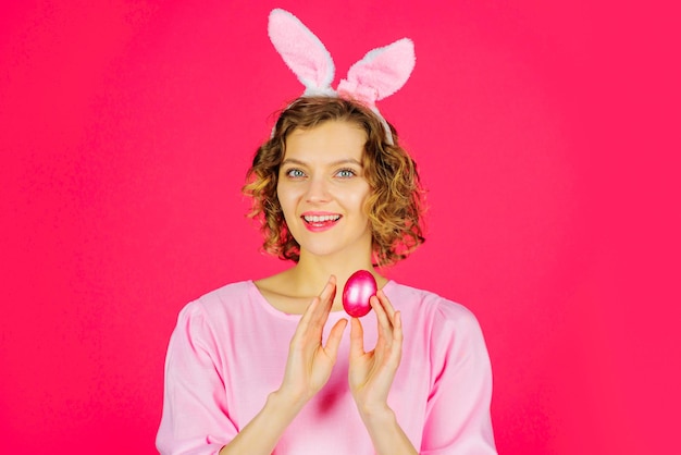 Feliz pascua niña sonriente con huevo rosa mujer de vacaciones de primavera en orejas de conejo cazando huevos