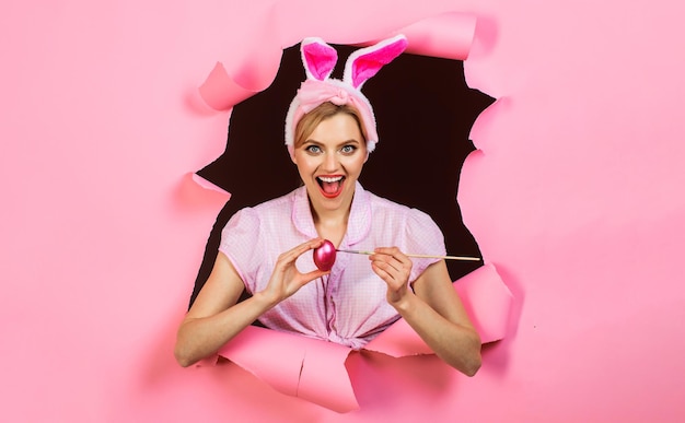 Feliz pascua niña sonriente en orejas de conejo pintando huevos conejo mujer con huevo rosa y pincel