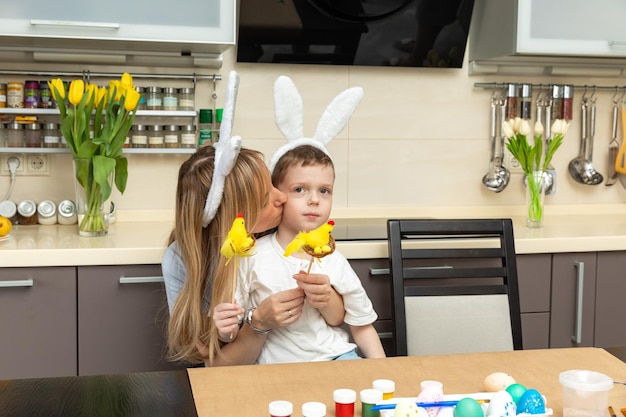 Feliz pascua niño niño y mamá con orejas liebre jugando preparándose para las vacaciones y pintando huevos