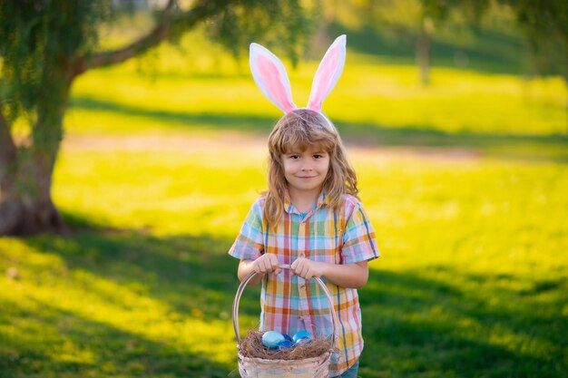 Feliz Pascua Niños niño en orejas de conejo cazando huevos de Pascua en el parque al aire libre