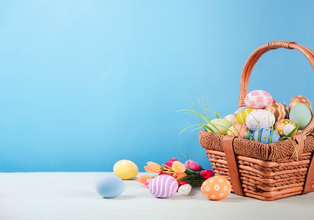 Feliz Pascua, Pascua pintó los huevos en la cesta en la mesa rústica de madera para su decoración en vacaciones. copia espacio