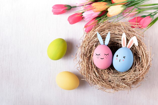 Feliz Pascua, Pascua pintó huevos en el nido en la mesa rústica de madera para su decoración en vacaciones. Vista superior con espacio de copia.