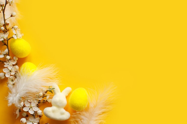 Feliz Pascua Pascua plana con huevos plumas de conejito y cereza floreciente sobre fondo amarillo Plantilla festiva moderna con espacio para texto Tarjeta de felicitación o pancarta