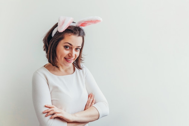 Feliz Pascua vacaciones celebración primavera concepto. Mujer joven con orejas de conejo aislados en la pared blanca. Preparación para vacaciones. Chica feliz y emocionada divirtiéndose el día de Pascua