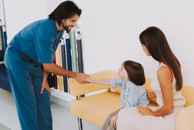 Feliz pediatra saluda a un niño pequeño sonriendo