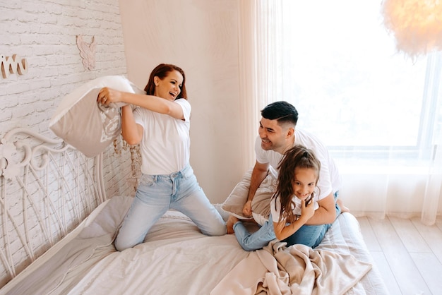 Foto feliz pelea de almohadas en familia en el dormitorio