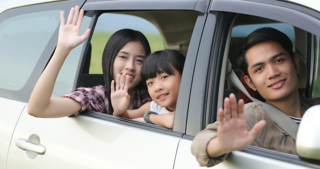 Feliz pequeña familia de niña sentada en el coche para disfrutar de viaje por carretera y vacaciones de verano