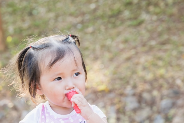 Feliz poco asiática chica comiendo jalea fresa en el parque