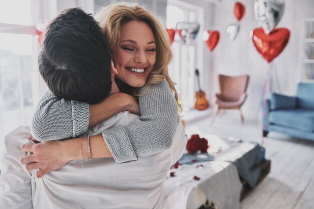 Feliz por estarmos juntos. Lindo casal jovem se abraçando e sorrindo enquanto passa um tempo no quarto