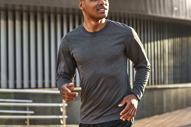 Feliz por ser saudável closeup retrato de um homem africano bonito e positivo em roupas esportivas começando