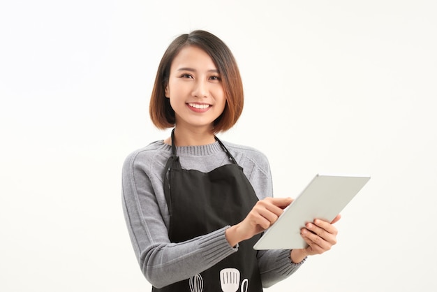 Feliz proprietário de uma pequena empresa com avental segurando um tablet em pé contra um fundo branco