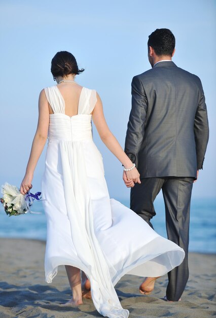 feliz recém casado jovem casal comemorando e se divertindo no belo pôr do sol na praia