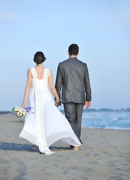 feliz recém casado jovem casal comemorando e se divertindo no belo pôr do sol na praia