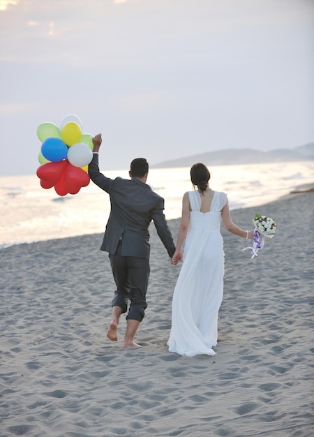 feliz recém casado jovem casal comemorando e se divertindo no belo pôr do sol na praia