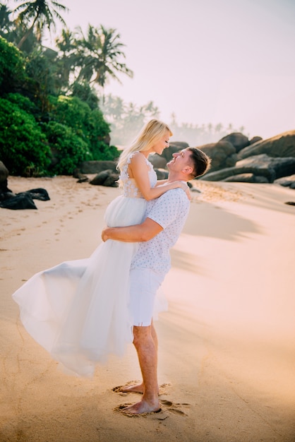 Feliz recién casados abrazando contra el fondo de la playa tropical